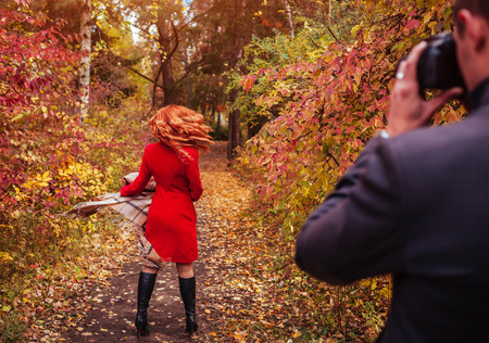 Man takes a picture of his girlfriend spinning using camera in autumn forestの写真素材