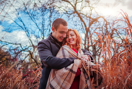 Young couple in love hugs in autumn forest among high grass. Happy people smilingの写真素材