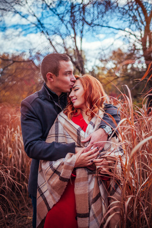 Young couple in love hugs in autumn forest among high grass. Happy people smilingの写真素材