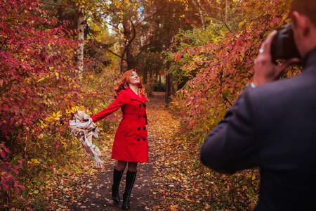 Man takes a picture of his girlfriend dancing using camera in autumn forestの写真素材