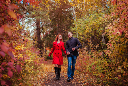 Young couple in love runs in autumn forest among colorful trees. People having funの写真素材
