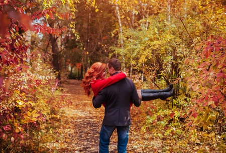 Young couple having fun in autumn forest. Man holds his woman in his arms and dancesの写真素材