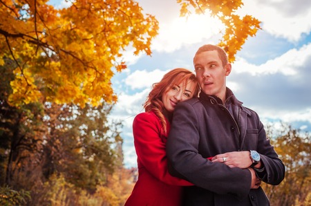 Young couple in love hugs in autumn forest among colorful trees. Romantic dateの写真素材