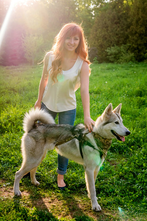 A young couple walking husky dog in summer park. Happy girl holding leashの写真素材
