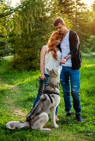 A young couple walking a dog in the spring park and hugging. Huskyの写真素材