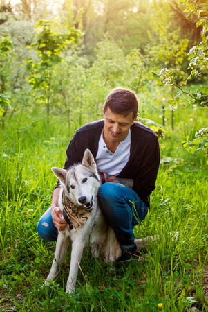A young couple walking husky dog in summer park. Happy master hugging his friendの写真素材