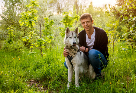 A young couple walking husky dog in summer park. Happy master hugging his friendの写真素材