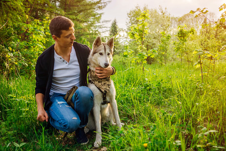 A young couple walking husky dog in summer park. Happy master hugging his friendの写真素材