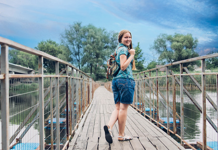 Teenager traveler girl walks across the bridge before rainの写真素材