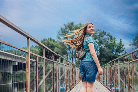Teenager traveler girl walks across the bridge before rainの写真素材
