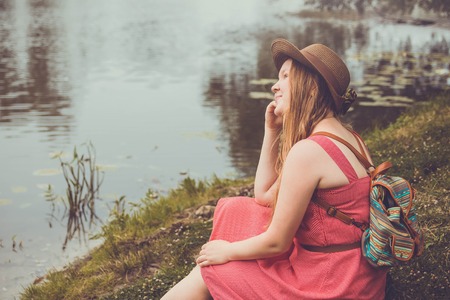Teenager traveler girl sits beside the river before rainの写真素材