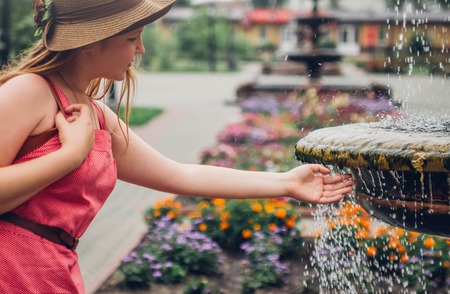 Teenager traveler girl washes hand in fountain on city streetの写真素材