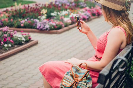 Teenager girl uses her phone in the park sitting on benchの写真素材