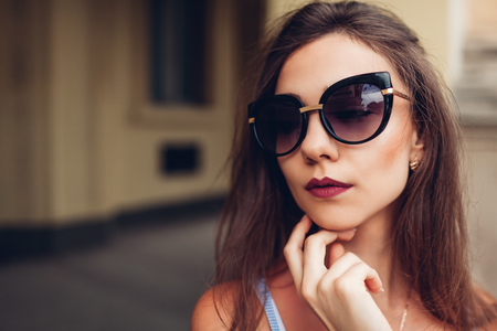 Outdoor portrait of young beautiful fashionable woman wearing stylish sunglasses. City fashion. Makeup. Close-upの写真素材