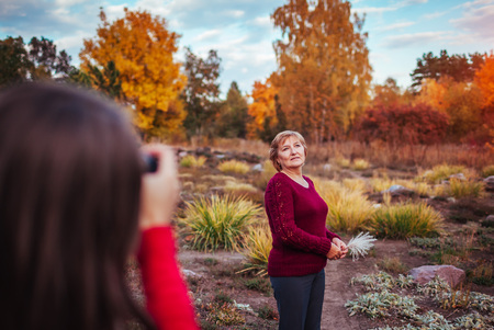 Photographer takes a picture of a middle-aged woman in autumn parkの写真素材