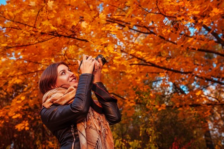 Young photographer takes pictures of autumn forest at sunsetの写真素材