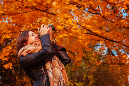 Young photographer takes pictures of autumn forest at sunsetの写真素材