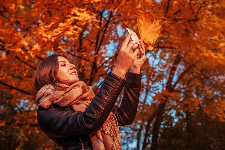 Young photographer takes pictures of autumn forest at sunsetの写真素材