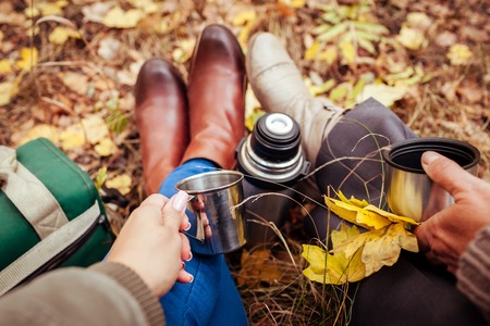 Two travellers having rest and drinking tea in autumn forestの写真素材