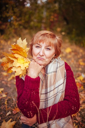 Middle-aged woman having fun in autumn forestの写真素材