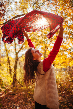 Young woman running with a scarf in autumn forestの写真素材