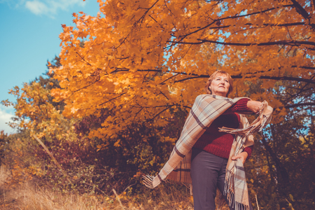 Middle-aged woman having fun in autumn forestの写真素材