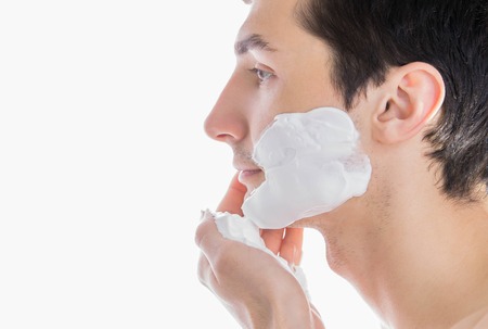 Man applying shaving foam on his face on white background. Close upの写真素材