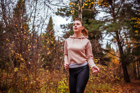 Young sportive woman running in autumn forest. Healthy lifestyle. Active way of lifeの写真素材