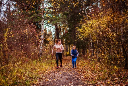 Little boy and his sportive sister running in autumn forestの写真素材