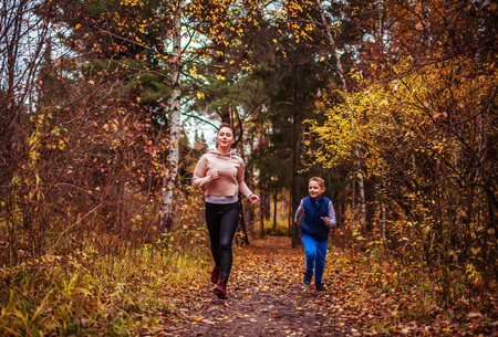 Little boy and his sportive sister running in autumn forestの写真素材