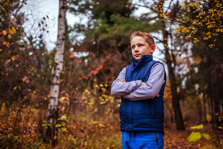 Little sportive boy having rest after exercises in autumn forestの写真素材