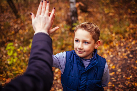 Little boy gives his sister high five after exercising in autumn forestの写真素材