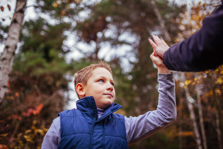 Little boy gives his sister high five after exercising in autumn forestの写真素材