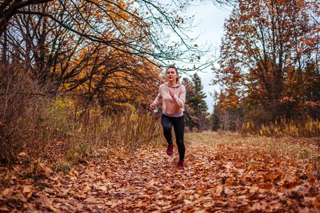 Young sportive woman running in autumn forest. Healthy lifestyle. Active way of lifeの写真素材