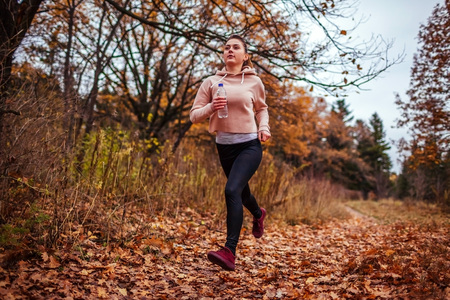 Young sportive woman running in autumn forest. Sport conceptの写真素材