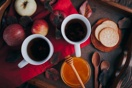 Hot tea with apples and honey on a wooden tray. Autumn harvestの写真素材
