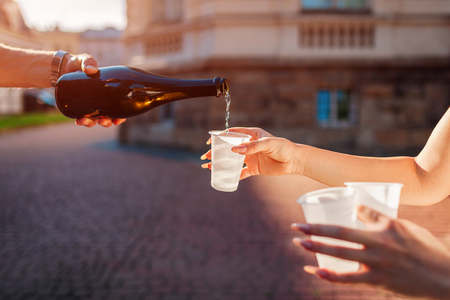 Man pours champagne while woman holding glasses outdoors. Party celebration. Birthdayの写真素材