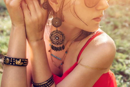 Woman wearing exotic jewellery and golden mehendi tattoo with red manicureの写真素材