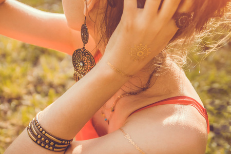 Woman wearing exotic jewellery and golden mehendi tattoo with red manicureの写真素材