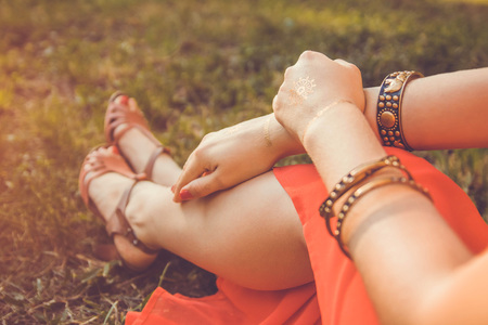 Woman wearing exotic jewellery and golden mehendi tattoo with red manicure