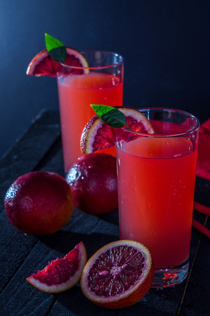 Homemade blood orange juice on black background. Refreshing summer cocktailの写真素材