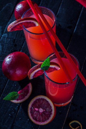 Homemade blood orange juice on black background. Refreshing summer cocktailの写真素材
