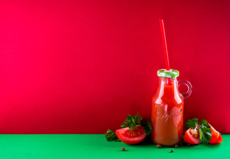 Tomato juice in the bottle on red background. Healthy drink. Spaceの写真素材