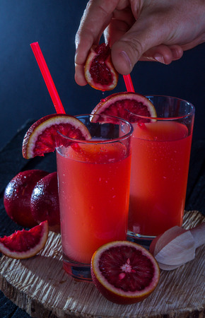 Homemade blood orange juice on black background. Refreshing summer cocktailの写真素材