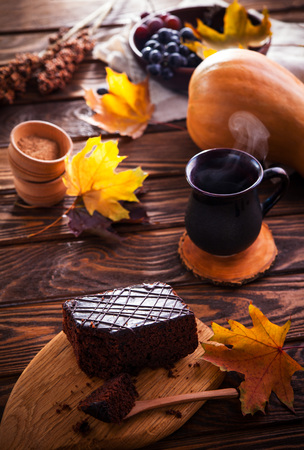 Chocolate brownie with a cup of coffee on wooden background. Autumn mood and cozinessの写真素材