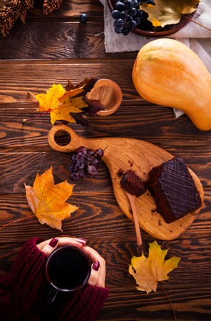 Woman is having a cup of coffee with chocolate brownie and fruits. Autumn cozinessの写真素材