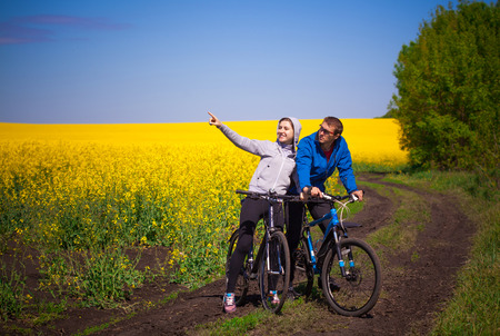 Young couple of bikers rides in spring rapeseed fieldの写真素材