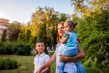 Happy family walking outdoors in park. Mother with two children son and daughter relaxing together.の写真素材
