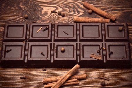 Chocolate bar and spices on wooden table. Dessert with cinnamon and clovesの写真素材