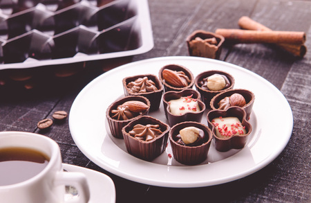 Coffe with assortment of chocolate candies on black wooden tableの写真素材
